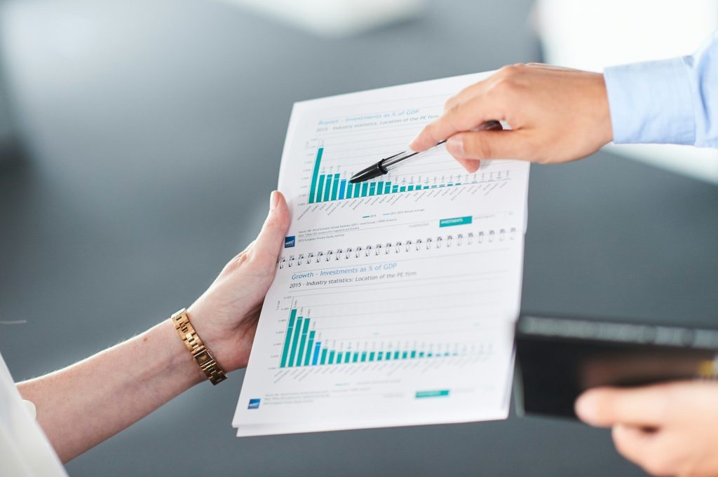 One hand holding a printed chart, another holding out a payment card