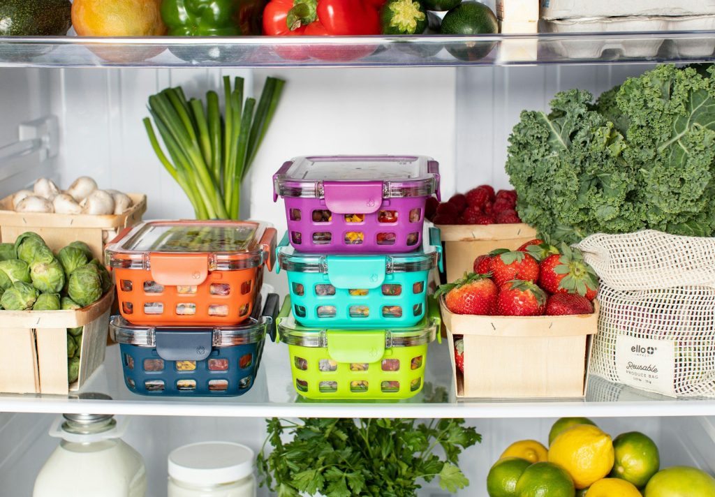 Refrigerator shelves packed with vegetables, berries and stacked containers