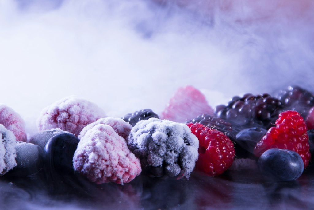 Frozen raspberries and blackberries in a drift of cold vapor