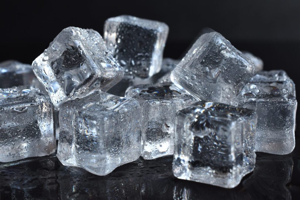 Clear ice cubes on a dark reflective surface