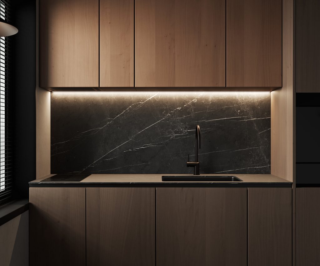 Dark kitchen with wood cabinetry and a black marble splashback under warm strip lighting
