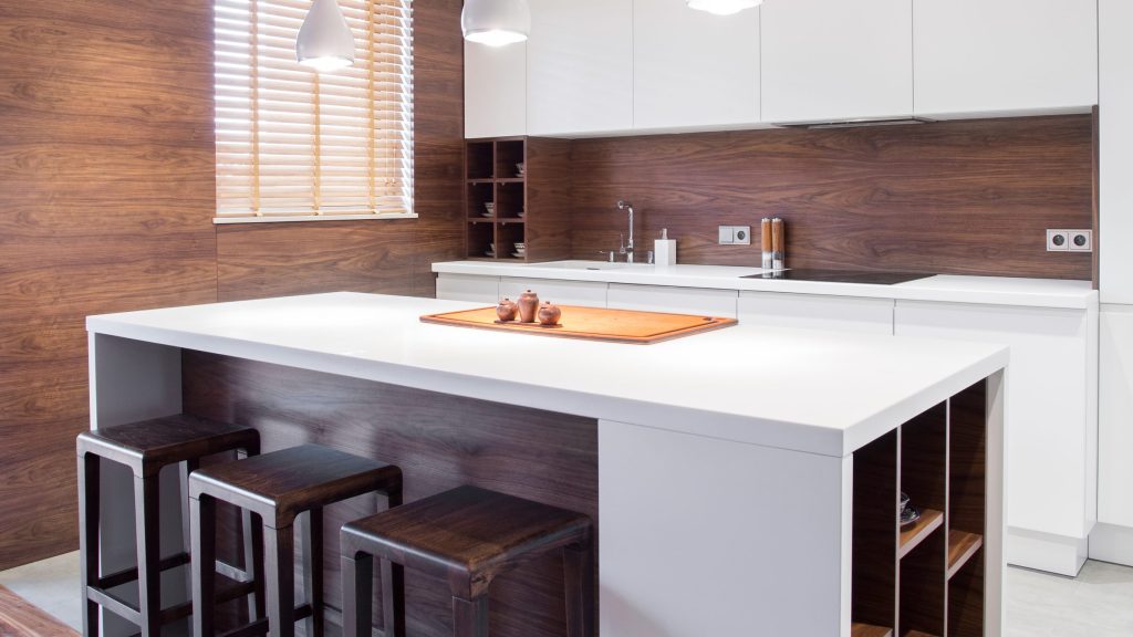 A walnut and white kitchen with a long island, timber stools and open shelving beneath the worktop