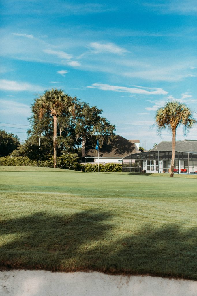 A golf green backed by houses with screened lanais and palm trees