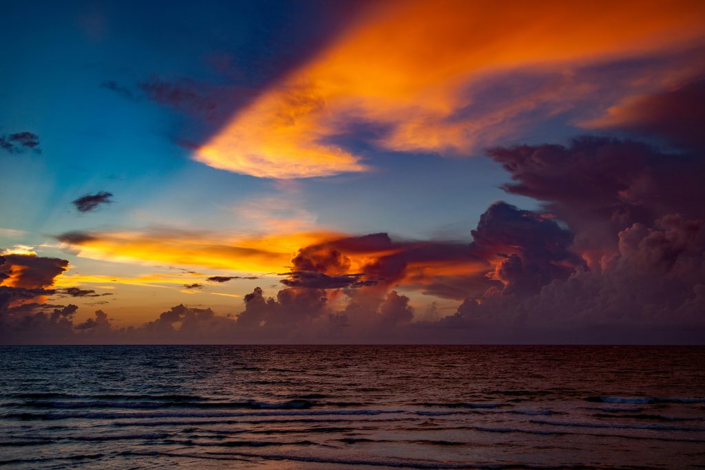 Storm clouds lit gold over the surf at sunset