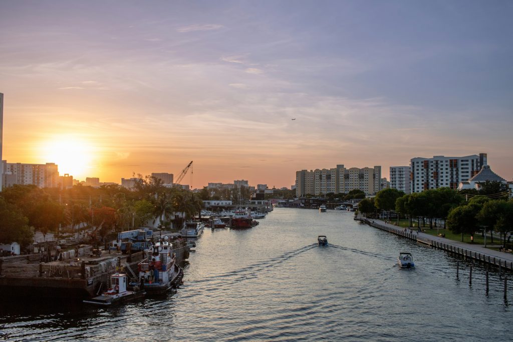The sun setting over a waterway with boats moored along both banks