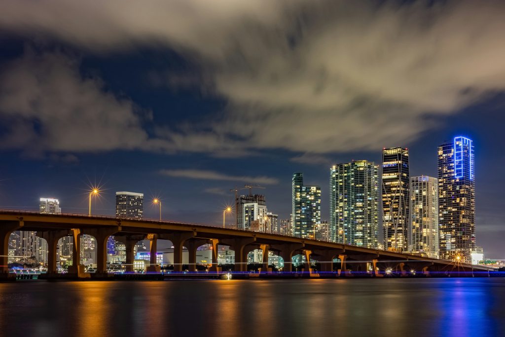 The causeway lit at night, with the skyline behind it