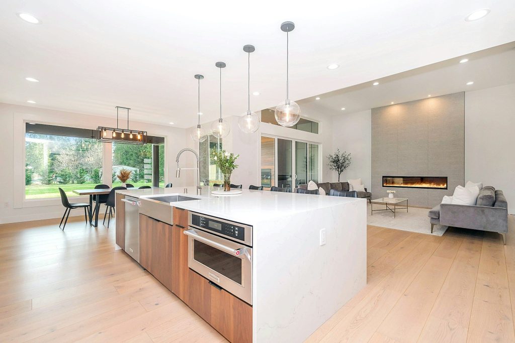 A long white island in an open-plan room with a linear fireplace beyond