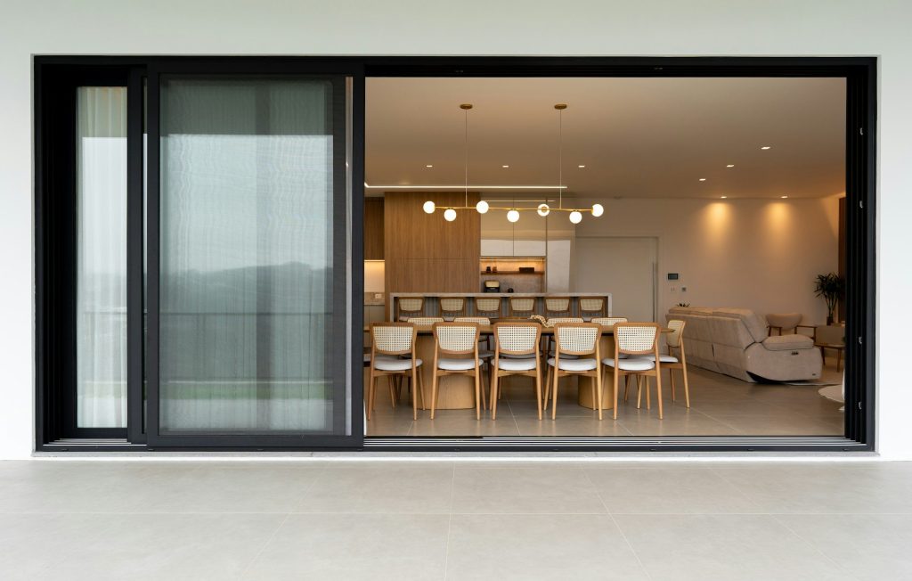 A dining room and kitchen seen from a terrace through an open sliding door