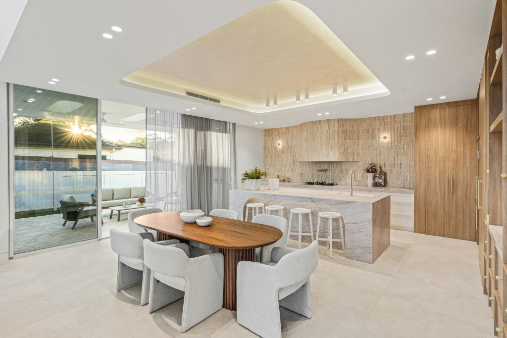 A travertine kitchen and an oval dining table, glazed to a terrace