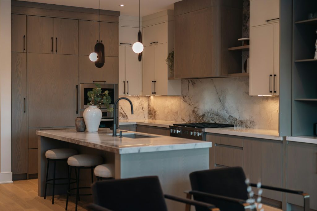 A walnut kitchen with a marble island, three stools and two pendants