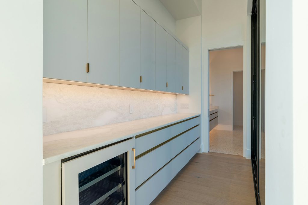 A pale blue run of drawers with a glass-fronted wine drawer built in
