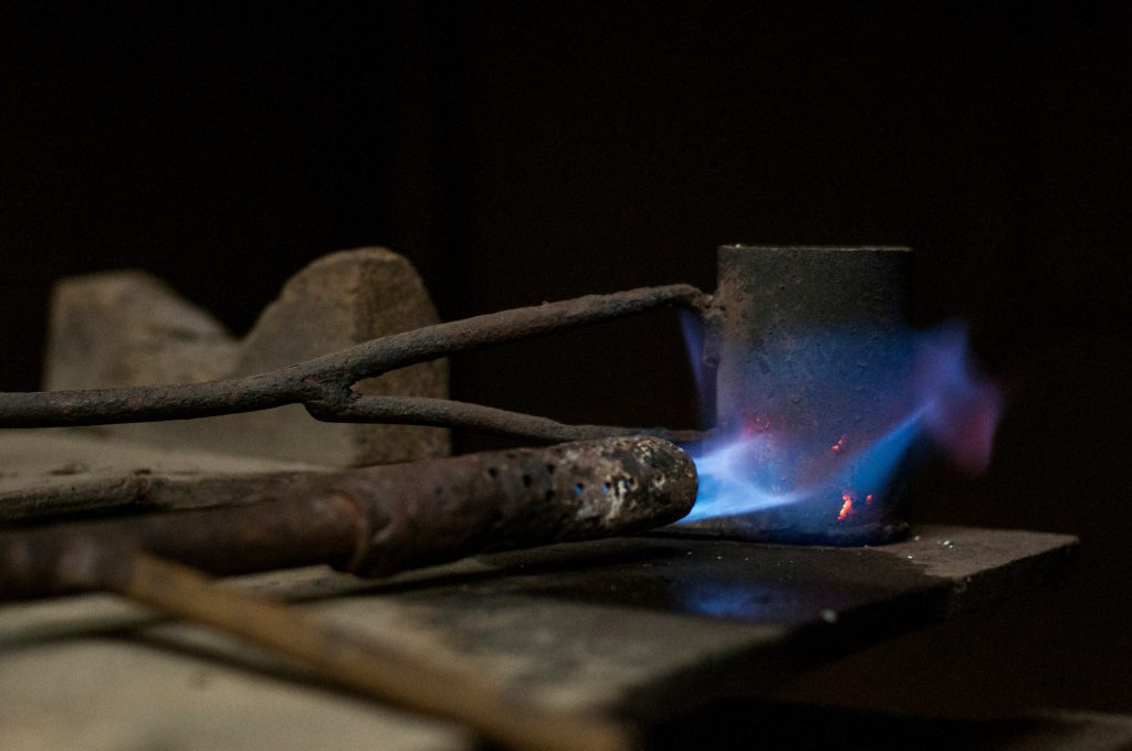 A blue brazing flame playing on a metal fitting