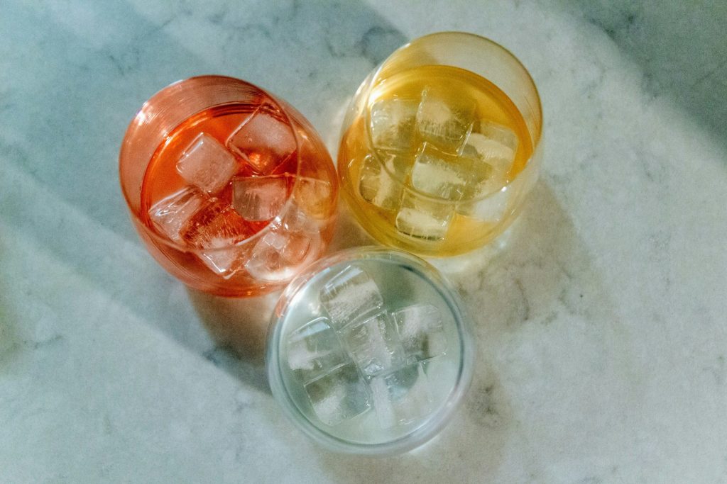 Three tumblers of iced drinks on a marble counter, the cubes clear and rounded