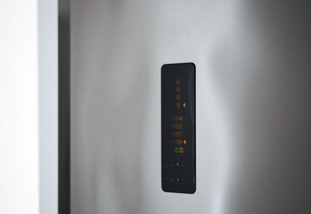 A slim control strip on a stainless refrigerator door, the temperature scale lit in amber