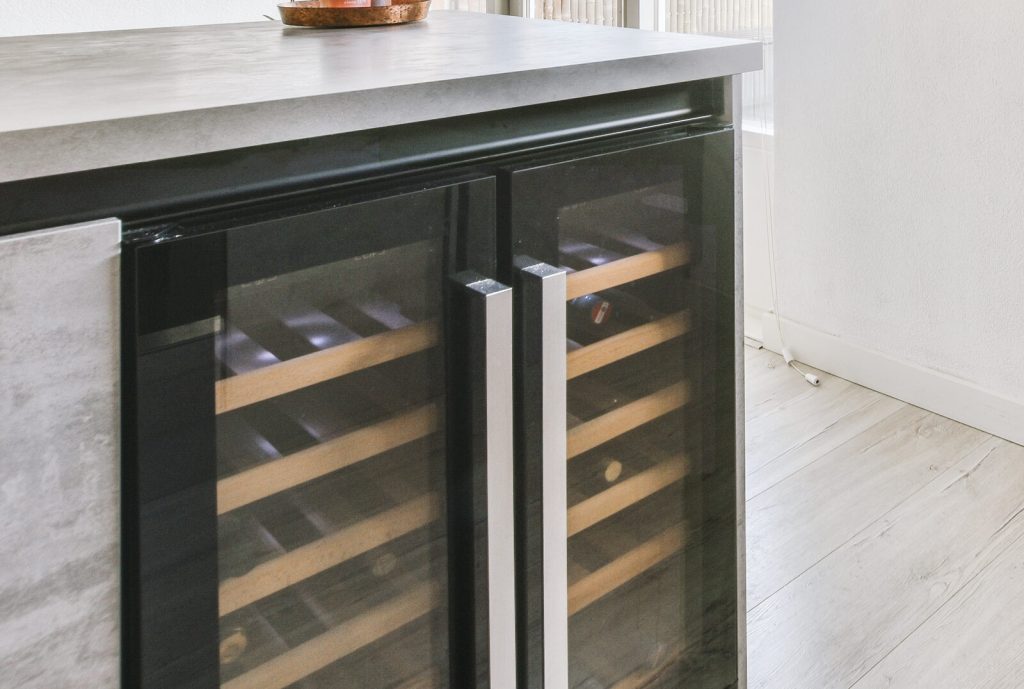 Undercounter wine cooler with glass doors built into a kitchen island